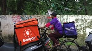 Delivery executive riding a bicycle with Swiggy and Zepto delivery bags, highlighting India’s growing quick commerce and e-retail sector.